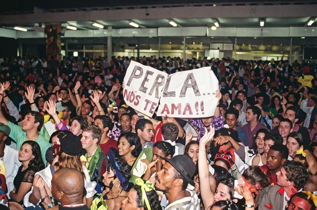 Multidão na Festa do Cafona, em Colatina, erguendo um cartaz escrito à mão